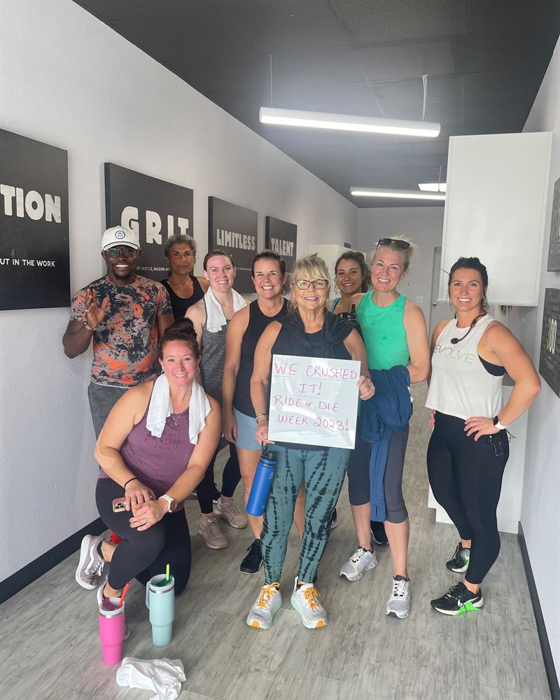 A group of smiling Revolve members posing together after class